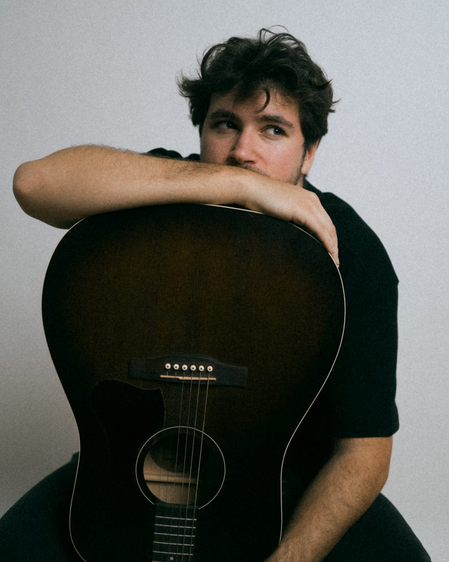 Côme, les bras croisés sur sa guitare